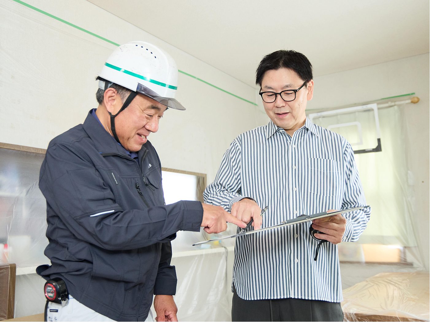 現場で打ち合わせをする大工と建築士
